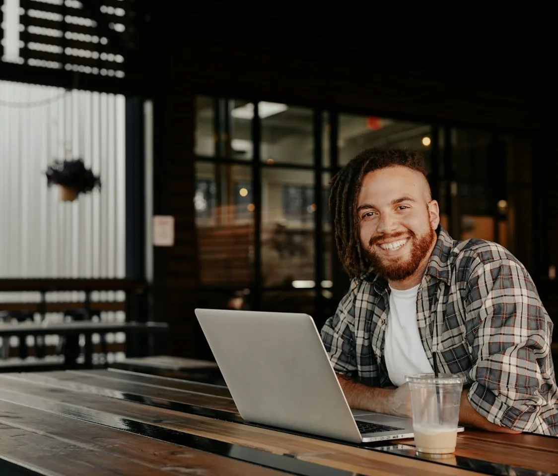Smiling man using a working laptop at a table
