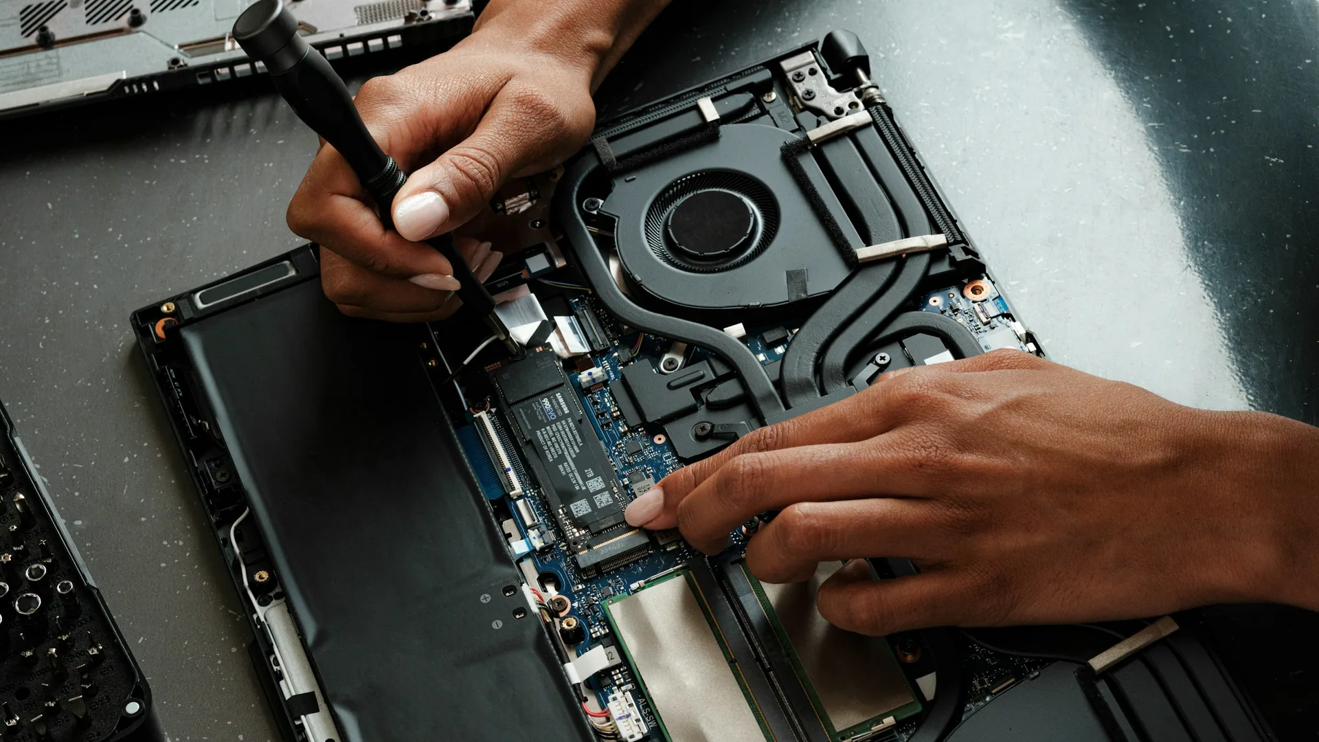 Technician repairing an open laptop during a service visit