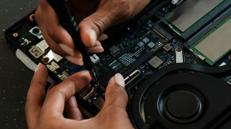 Technician's hands installing a new SSD in an open laptop